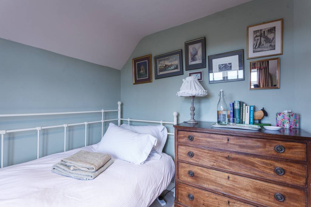 Single bedroom with blue-green walls and antique dresser